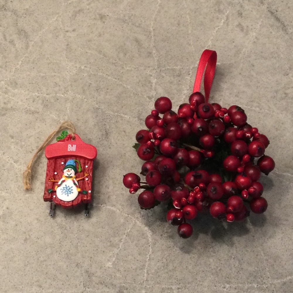 Christmas ornaments: one faux red berry wreath and one sled with the name “Bill”